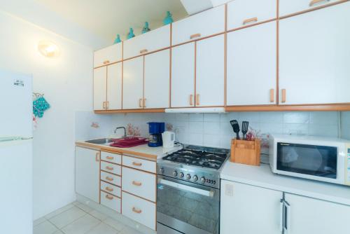 a kitchen with white cabinets and a stove and a microwave at Royal Palm Holiday Apartment in Méro