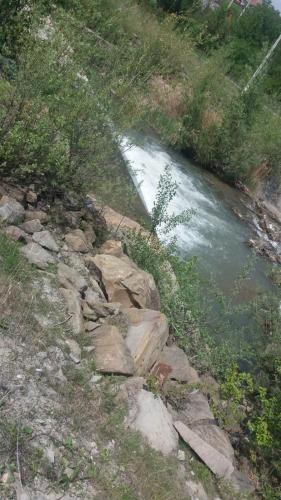 a stream of water with rocks next to a river at Pensiunea Dely_Cios in Vălenii de Munte