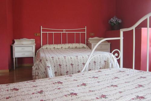 a bedroom with two beds and red walls at Agroturismo Abaienea in Vitoria-Gasteiz