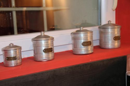 four metal canisters sitting on a red shelf at La carpe diem in Bédoin