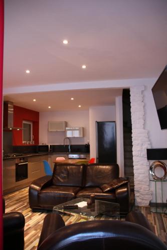 a living room with a leather couch and a kitchen at La carpe diem in Bédoin