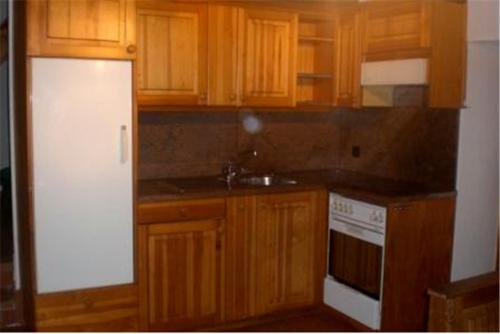 eine Küche mit Holzschränken und einem weißen Kühlschrank in der Unterkunft Casa Arcuri in Giumaglio