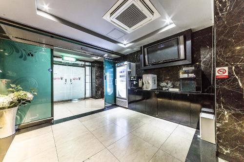 a room with a kitchen and a tv on a wall at Jamsil Tomgi Hotel in Seoul