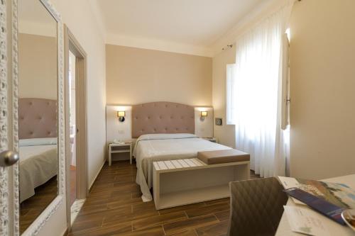 una camera d'albergo con letto e specchio di Albergo Battelli a Marina di Pietrasanta