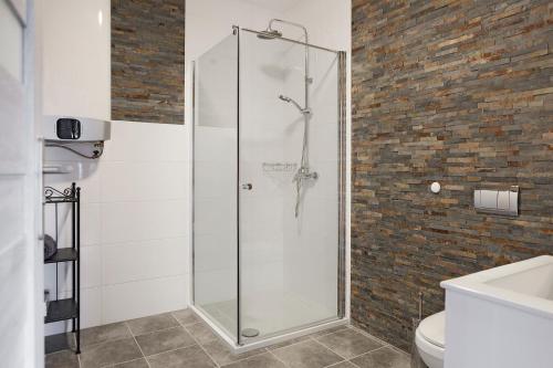 a glass shower in a bathroom with a brick wall at Apartamenty w Starym Browarze 3 in Kłodzko