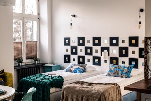 dwa łóżka w pokoju ze ścianą z obrazami w obiekcie BOHO Apartments w Łodzi