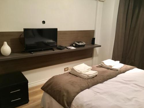 1 dormitorio con 1 cama y TV de pantalla plana en Quintana Suite en Buenos Aires