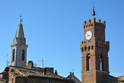 two towers of a building with a clock tower at La Bellavita B&B in Pienza