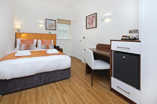a bedroom with a bed and a desk and a computer at Imperial Guest House Ltd. in Hounslow