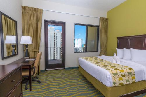 a hotel room with a bed and a desk and windows at Edge Hotel Clearwater Beach in Clearwater Beach