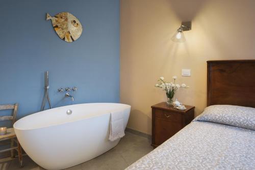 a bathroom with a white bath tub next to a bed at La Bellavita B&B in Pienza