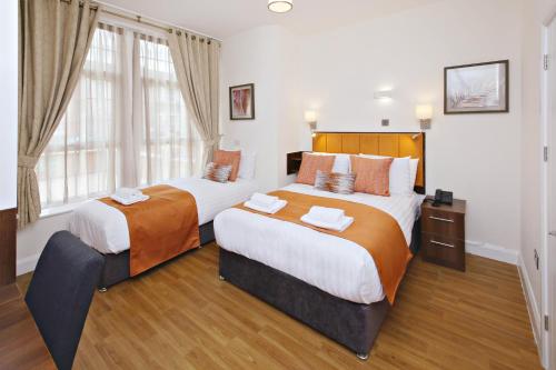 a bedroom with two beds and a window at Imperial Guest House Ltd. in Hounslow