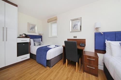 a hotel room with a desk and a bed and a desk at Imperial Guest House Ltd. in Hounslow