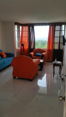 a living room with orange furniture and windows at Malia's New Kgn Apartment in Kingston