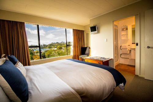 um quarto de hotel com uma cama grande e uma janela grande em Kowhai Lane Lodge em Half-moon Bay