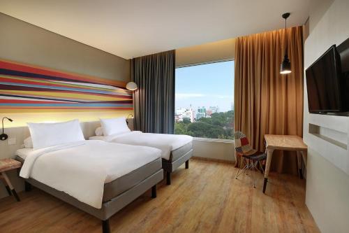 a hotel room with two beds and a large window at Ibis Styles Makassar Sam Ratulangi in Makassar