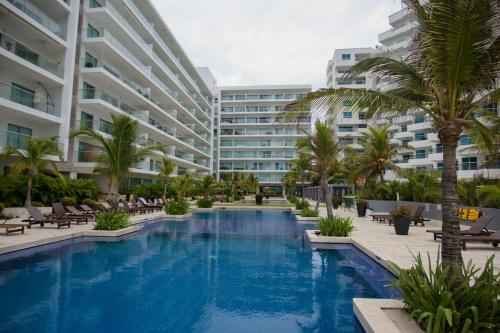 uma piscina com cadeiras e palmeiras em frente a um edifício em Morros Epic 222 em Cartagena de Indias