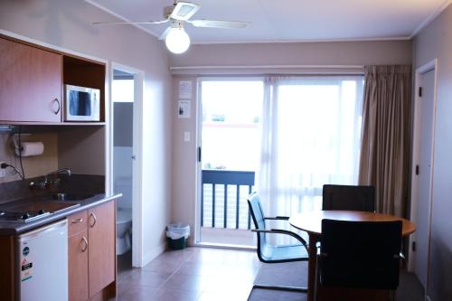 a kitchen and dining room with a table and a balcony at Kiwi Studios Motel in Palmerston North