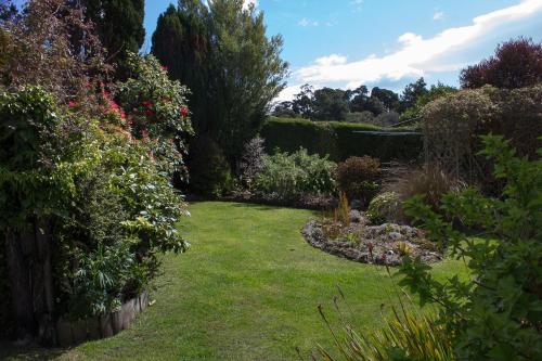 a garden with a lawn with flowers and plants at Kowhai Lane Lodge in Half-moon Bay