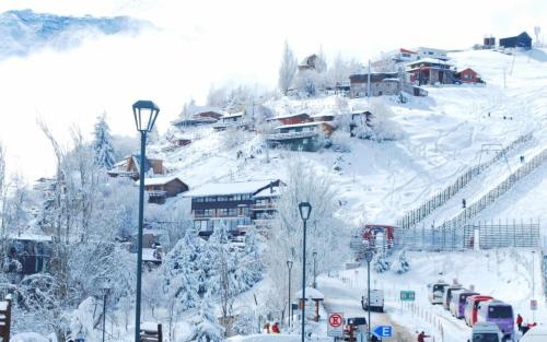 a snow covered mountain with a town with buildings at Hotel HF in Farellones