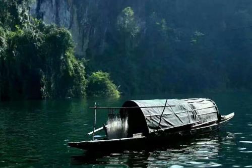 a boat with a cover sitting in the water at 372 Jingjing Home in Yongshun