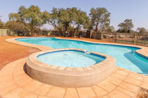 a large swimming pool with a wooden coping around it at Kareespruit Game Ranch & Guest House in Zeerust