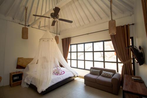 a bedroom with a bed with a mosquito net at Gili Breeze Tropical Bungalows in Gili Trawangan