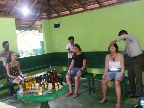 a group of people sitting around a table with bottles at Jungle Village Homestay in Pinnawala