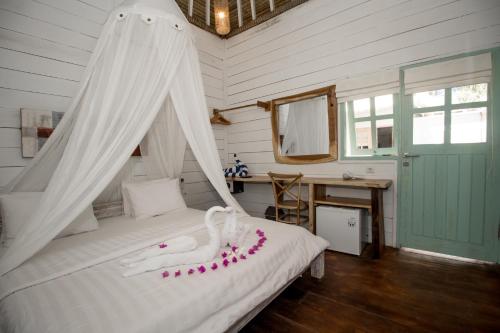 a bedroom with a bed with a white canopy at Gili Breeze Tropical Bungalows in Gili Trawangan