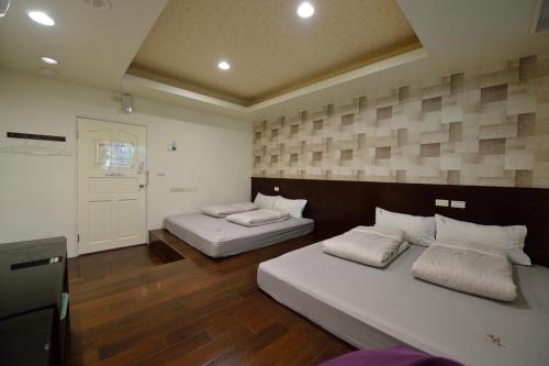 two beds in a large room with wooden floors at 溪頭吉野民宿Ji-Ye in Lugu
