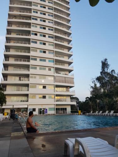 a man sitting in a swimming pool next to a large building at View Talay 6 Pattaya in Pattaya