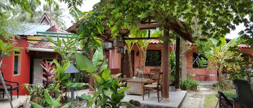 a garden with a pergola in front of a house at the coconut langkawi in Pantai Cenang