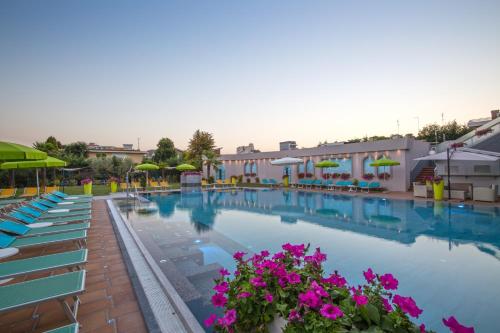 a swimming pool with blue chairs and purple flowers at Hotel Terme Cristoforo in Abano Terme