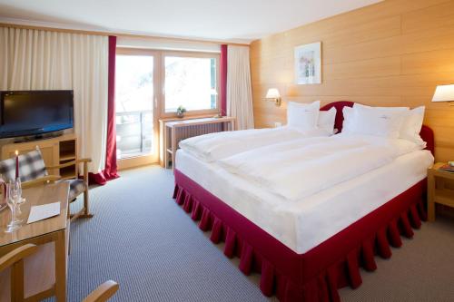 a hotel room with a large bed and a television at Hotel Angela in Lech am Arlberg