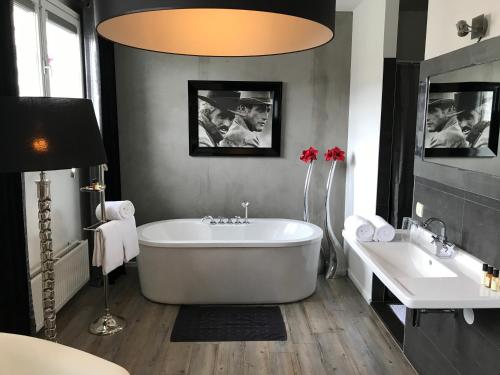 a bathroom with a large tub and a sink and a tub at Hotel Huis van Bewaring - Bijzonder boutique hotel in historisch pand in Almelo
