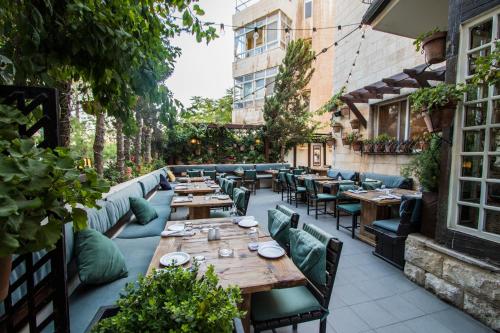 un restaurante al aire libre con mesas de madera y sillas verdes en Bonita Inn, en Amán