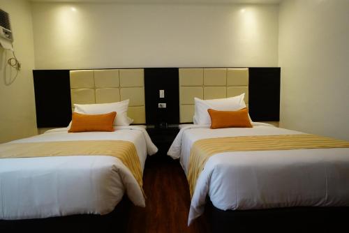 two beds in a hotel room with orange pillows at Hotel Oazis in Butuan