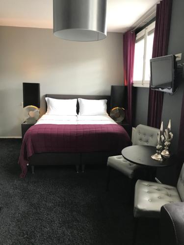 a bedroom with a bed and a table and a tv at Hotel Huis van Bewaring - Bijzonder boutique hotel in historisch pand in Almelo