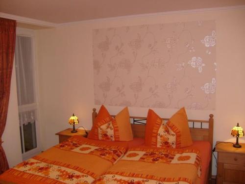 グラール・ミューリッツにあるHaus Bucheneckのベッドルーム1室(オレンジ色の枕が備わるベッド2台付)