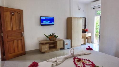 a room with a bed and a tv on the wall at Rasdhoo Island Inn Beachfront in Rasdu