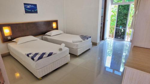 2 camas y un sofá en una habitación con ventana en Rasdhoo Island Inn Beachfront, en Rasdu