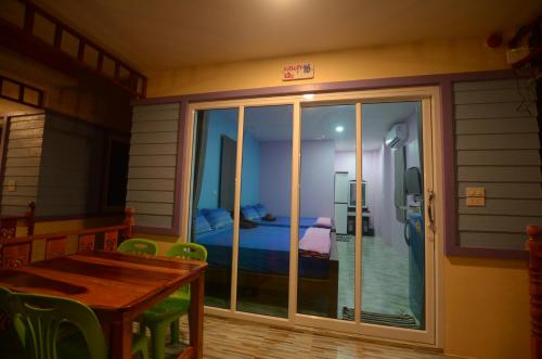 Habitación con puerta corredera de cristal y mesa. en Sansook Chaolao, en Chao Lao Beach