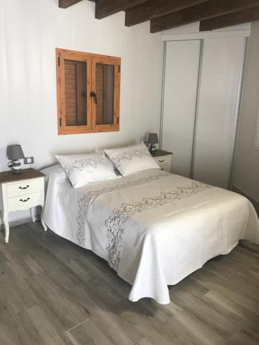 a bedroom with a white bed and a wooden floor at Casa Elisa Canarias in Fátaga