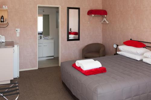 a bedroom with a bed with red and white pillows at Motel Te Kuiti in Te Kuiti