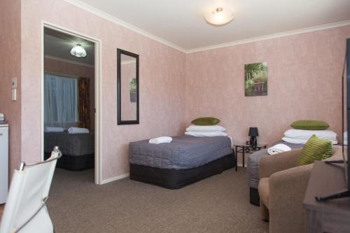 a hotel room with two beds and a couch at Motel Te Kuiti in Te Kuiti