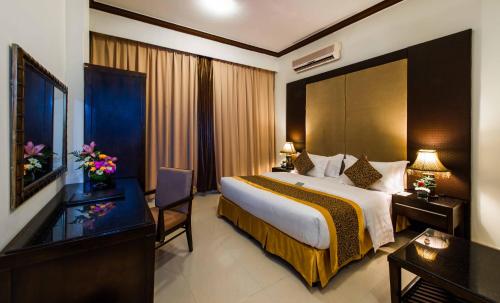 a hotel room with a large bed and a desk at Boudl Buraydah in Buraydah