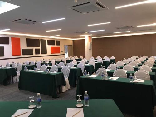 a conference room with green tables and white chairs at Bei Boutique Hotel in Muar