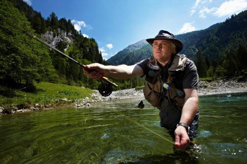a man in the water holding a rod in a river at Haus Fercher in Grossarl