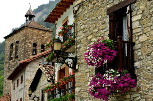 a building with flowers on the windows and a clock tower at Argonz Etxea in Urzainqui