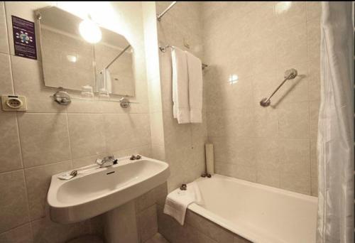 a white bathroom with a sink and a bath tub at Hotel Palanca in Porto